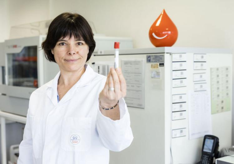 Technicienne de laboratoire tenant un tube d'analyse sanguine